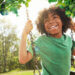 Child swinging on a swing by the forest.