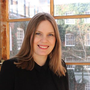 Bio photo of woman standing in front of window smiling at camera