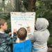 three kids writing on a large paper