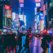 New York City street at night with people walking and cars.