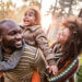 happy parents in nature holding a child on the dads back