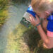 kid looking through a scope made out of a milk carton at water