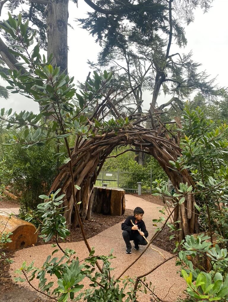 child plays under arc feature in outdoor park