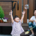 child playing with bubbles and father sitting nearby watching