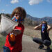 kid with mask holding a net and mother with mask crouching in the back