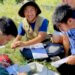 Five students sit outside in a field taking ecological observations.