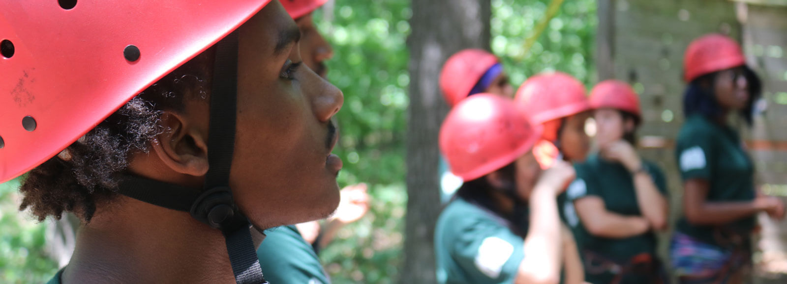 Youth wearing helmets getting ready to climb.