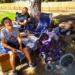 family sitting in a shady spot under a tree, lounging and relaxing